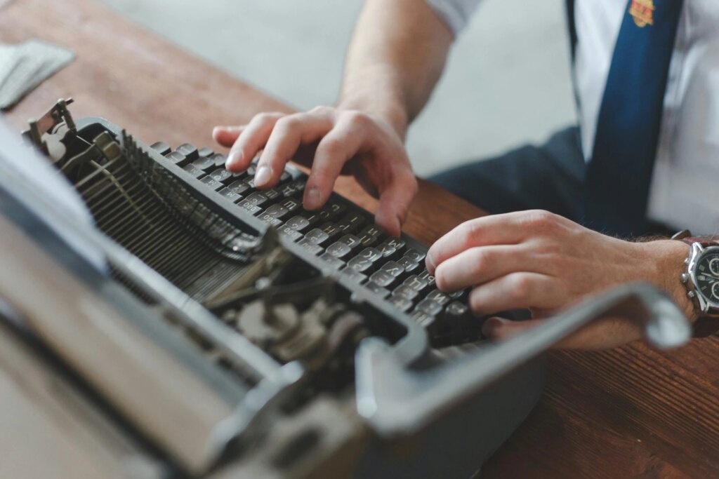 A man in a tie types on an old typewriter.